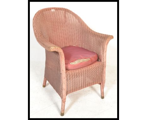 A vintage early to mid 20th Century Lloyd Loom conservatory / garden wicker style armchair, having a shaped back with scrolle