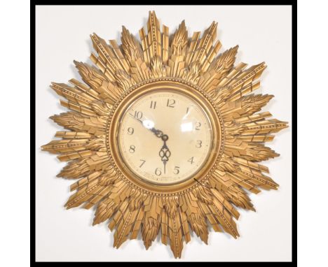 A vintage 20th Century Art Deco type sunburst starburst rising sun wall clock having a gilt decorated wooden frame. Central g