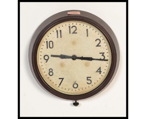 A vintage mid 20th Century industrial school wall clock having a round white face with arabic numerals to the chapter ring, s