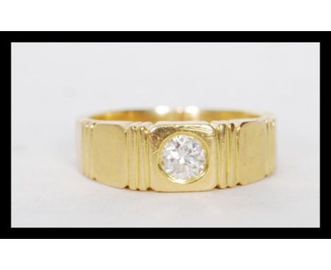 A stamped 18ct gold ring set with a brilliant cut diamond having stepped design shoulders. Weight 5.9g. Estimated diamond siz