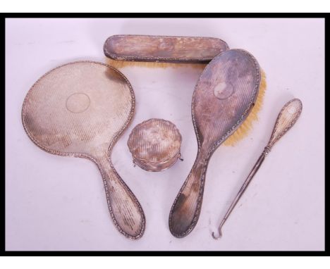 An early 20th Century silver hallmarked dressing table set consisting of hand held mirror, clothes brush, hair brush, button 