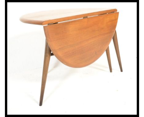 An Ercol retro 1970's drop leaf circular coffee - occasional table by Ercol raised on tapered legs with chamfered edge table 