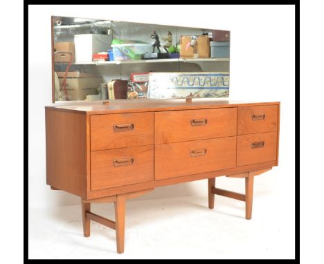 A vintage 1960's teak wood dressing table / sideboard having a configuration of six draws with insert handles raised on taper