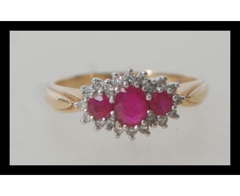 A hallmarked 9ct gold diamond and ruby triple squashed cluster ring having 23 stones consisting of three round rubies with 20