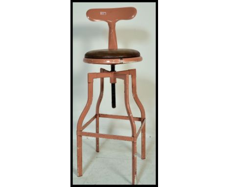 A vintage retro 20th Century machinist stool raised on tubular adjustable swivel legs and base with leather seat and T shaped