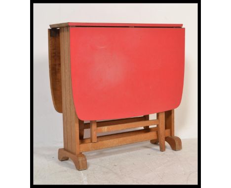 A retro vintage mid 20th Century red formica drop leaf dining table raised on square beech wood supports. Measures 76 cm high