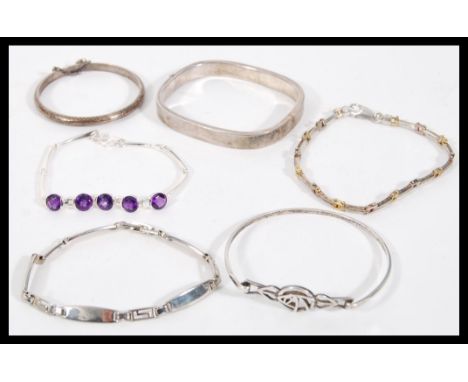 A selection of silver bracelets to include a square bangle with a hinge opening, a child's bangle with hinge opening and safe