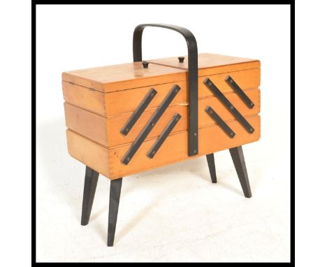 A vintage 20th Century beech wood concertina metamorphic action sewing / work box, ebonised carry handle to the top raised on
