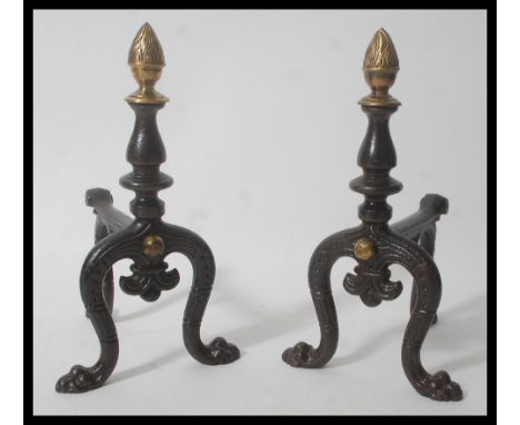 A pair of 19th Century Victorian cast metal fireside irons dogs having a painted ebonised lacquer finish with large gilt bras
