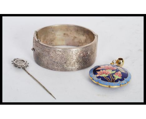 A silver hallmarked bangle bracelet having scrolled foliate and greek key engraving with a hinged opening (hallmarked Chester