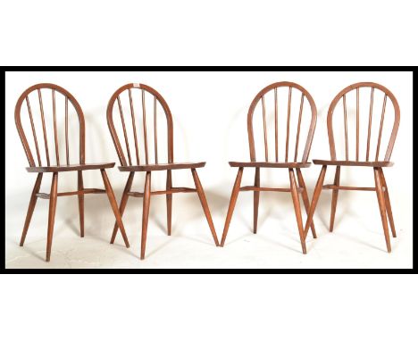 A set of four 1960's ercol beech wood hoop back dining chairs having tapering supports finish in mahogany color. Measures 85 