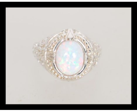 A stamped 925 silver dress ring set with an opal cabochon with pierced decoration celtic knot design shoulders. Weight 5.7g. 