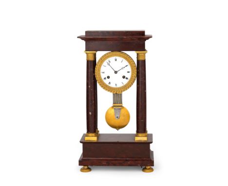 orologio a portico realizzato in marmo rosso di Francia, poggiante su quattro piedini godronati che sorreggono un basamento a
