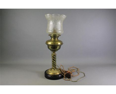 A Victorian Oil Lamp. The lamp having a brass stand and reservoir on black glazed porcelain base and a etched glass shade, ap