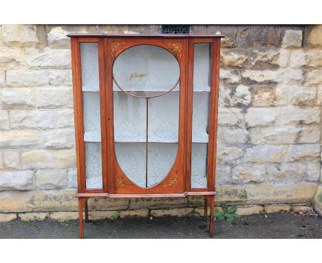 An Edwardian Display Cabinet. The cabinet with an oval glazed door, marquetry decoration with decorative two-toned foliate in