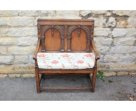 An Antique Oak Bench. The bench with decorative blind carving to the back and a panel seat, approx 92 x 112 x 72 cms.