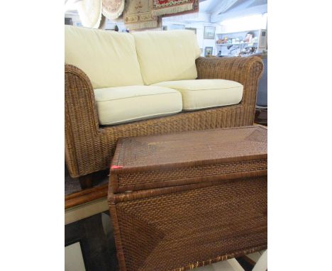 A modern Indonesian two seater wicker sofa with cream cushions together with a wicker basket housing two cream cushions 