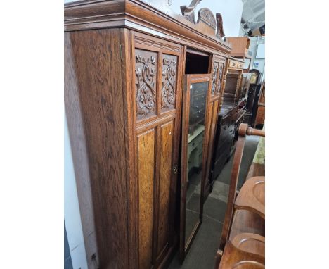 A late Victorian oak triple wardrobe with carved and pollard oak panels and central mirrored door, width 193cm. Condition- go