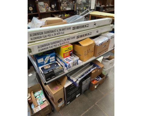 A large quantity (table top and one side on floor) of boxed and unused household items including 3 flagpoles with flags, rota