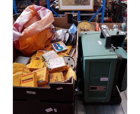 Two boxes of assorted film reels and a 16mm Bell &amp; Howell 1592 projector