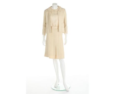 A Chanel couture ivory tweed suit, 1964, broad label and numbered 24873, the jacket with gilt lion mask buttons, the skirt wi