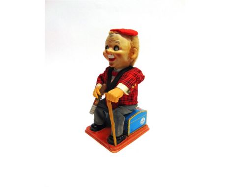 A NOMURA TOYS (JAPAN) BATTERY-OPERATED TINPLATE AND PLASTIC TOY FIGURE in the form of a cigar-smoking gentleman seated upon a