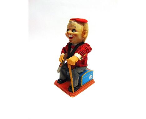 A NOMURA TOYS (JAPAN) BATTERY-OPERATED TINPLATE AND PLASTIC TOY FIGURE in the form of a cigar-smoking gentleman seated upon a