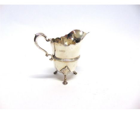 AN EDWARDIAN SILVER CREAM JUG possibly by Wakely & Wheeler (mark rubbed), London 1910, of cut rim helmet shape with moulded g