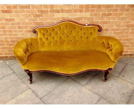 A VICTORIAN CARVED MAHOGANY FRAMED BUTTON UPHOLSTERED SOFA,  with shaped back and deep serpentine seat on carved cabriole sup