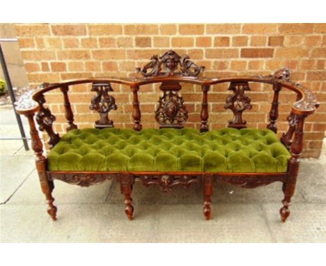 A HIGHLY CARVED WALNUT SOFA,  probably Continental, decorated with cherub and lion masks, griffons and fruit, drop-in button 