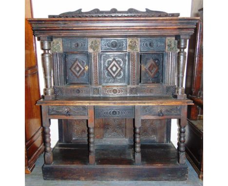 A LARGE CARVED OAK COURT CUPBOARD,  the upper section with moulded frieze and turned columns, the base with two drawers and p