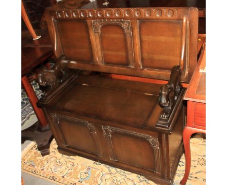 A monks oak bench with carved lion armrests and panelled design, on bracket supports, 41 1/2" wide
