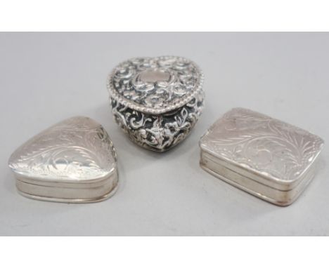 A silver trinket box with embossed decoration and two modern silver pill boxes with engraved decoration