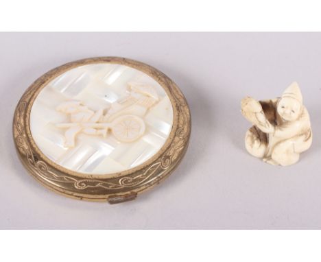 A carved ivory netsuke, formed as a crouching figure, and a powder compact, decorated with a rickshaw