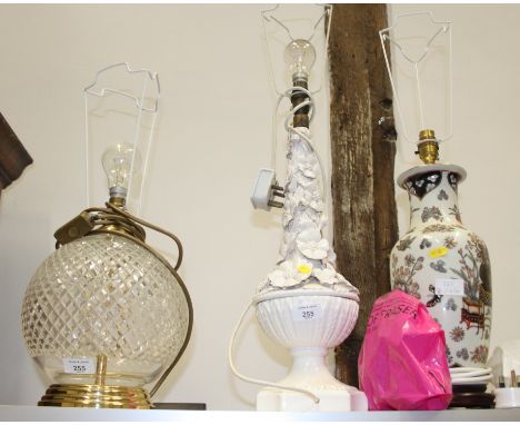 A cut glass and brass spherical table lamp with a floral relief decorated table and one other 