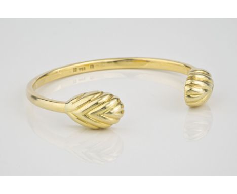 An 18ct yellow gold Torq style bangle with shell form terminals.  