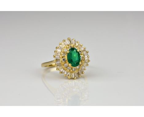 An 18ct gold, emerald and diamond cluster ring the oval cut emerald within a two tier ballerina style cluster of brilliant an