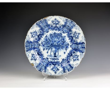 An 18th century Dutch Delft 'Peacock' pattern charger with barbed rim, painted with urn holding a floral bouquet and peacock 