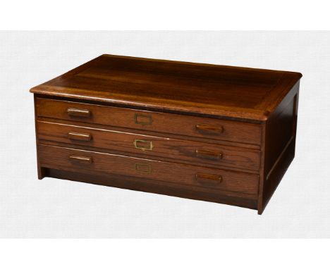 A 1920s oak three drawer plan chest with panelled sides, wooden bracket handles and brass name plates, 46 x 33¼in. (117 x 84.