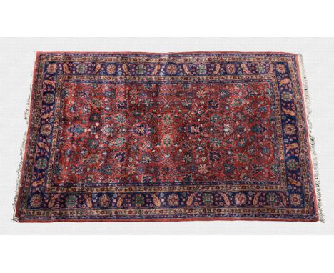 A Persian rug third quarter 20th century, the madder field with all over decoration of flowers and vines in dark blue, pink, 