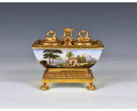 A Continental porcelain sarcophagus shaped inkstand the curved sides with painted country scenes, on a gilded base with ogee 
