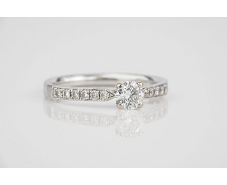 An 18ct white gold and diamond ring the central brilliant cut diamond, approx. 0.25ct over diamond set shoulders with millegr
