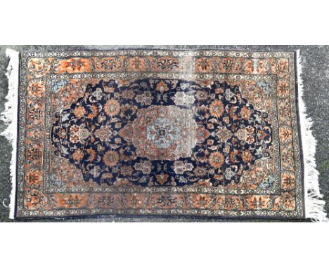 A small Persian rug the central light brown and pale blue pendant medallion on a dark blue field with all over floral decorat