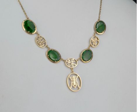 A Chinese 14ct gold and jade necklet with four oval polished green jade stones divided by and suspending pierced gold Chinese