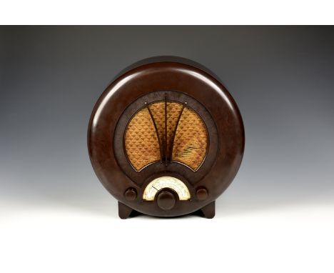 An Art Deco Ecko Type AD75 bakelite radio with circular brown bakelite case, quilted fabric speaker grille, 14¼in. (36.2cm.) 