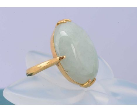 A continental yellow metal and jadeite jade dress ring, oval cabochon in four claw setting, ring size P, marked 22k to inner 