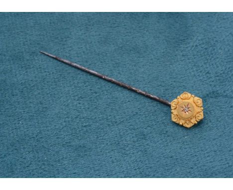A 15ct gold and diamond set stick pin, base metal pin, hexagonal mount with raised circular centre, diamond chip in gypsy set
