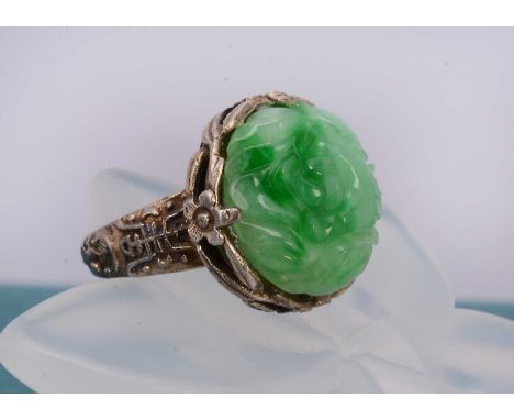 A Chinese jadeite jade dress ring, with carved floral cabochon within a decorative Chinese character marked silver mount and 