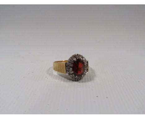 A VINTAGE 18CT GOLD LADIES GEMSET DRESS RING, the central oval faceted red stone surrounded by small illusion set diamonds, a