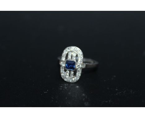 AN ART DECO STYLE SAPPHIRE AND DIAMOND RING, set with a central Princess cut blue sapphire and surrounded by thirty brilliant